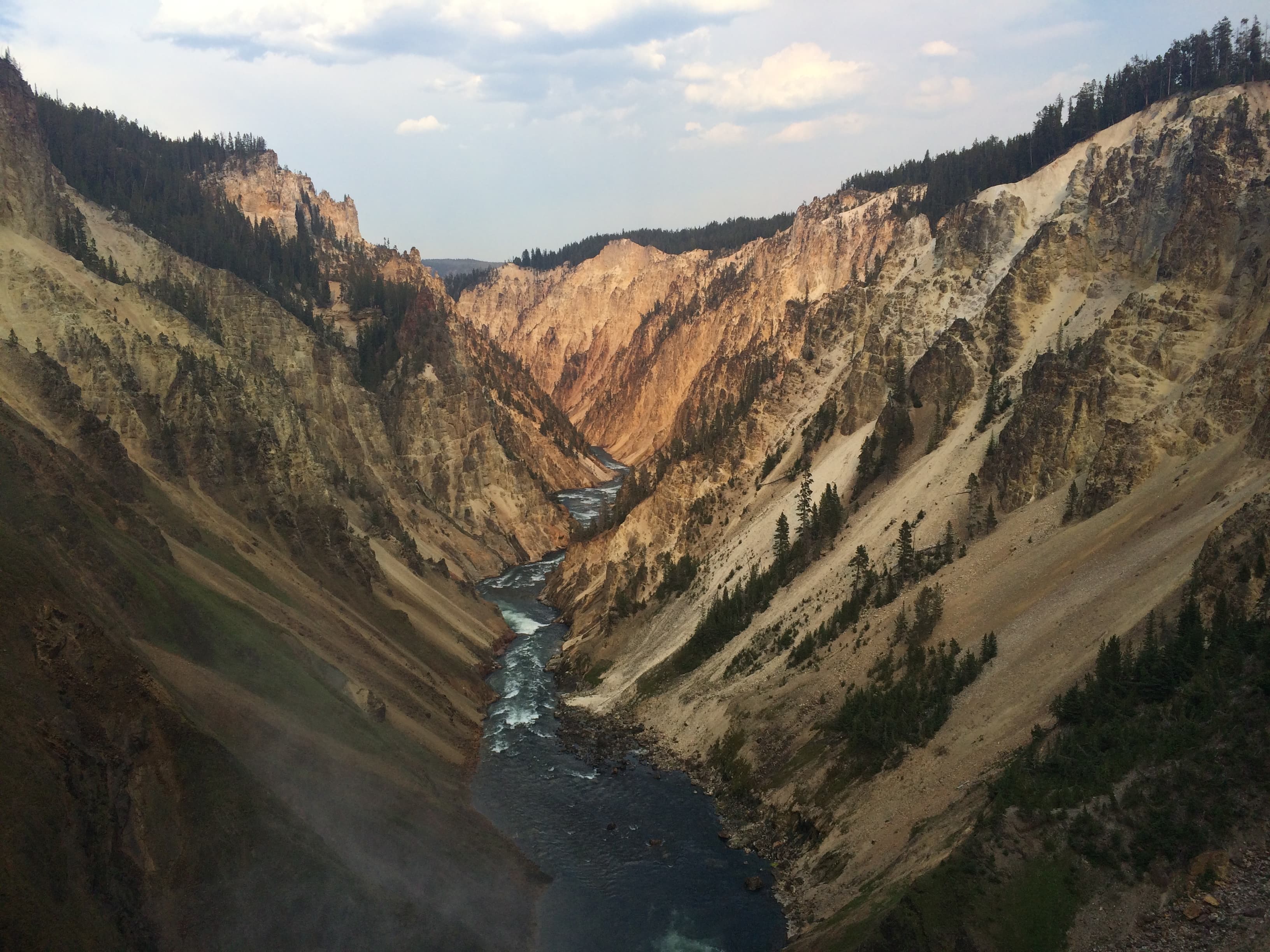 The Grand Canyon of the Yellowstone at dusk, the river running through steep pale cliffs.